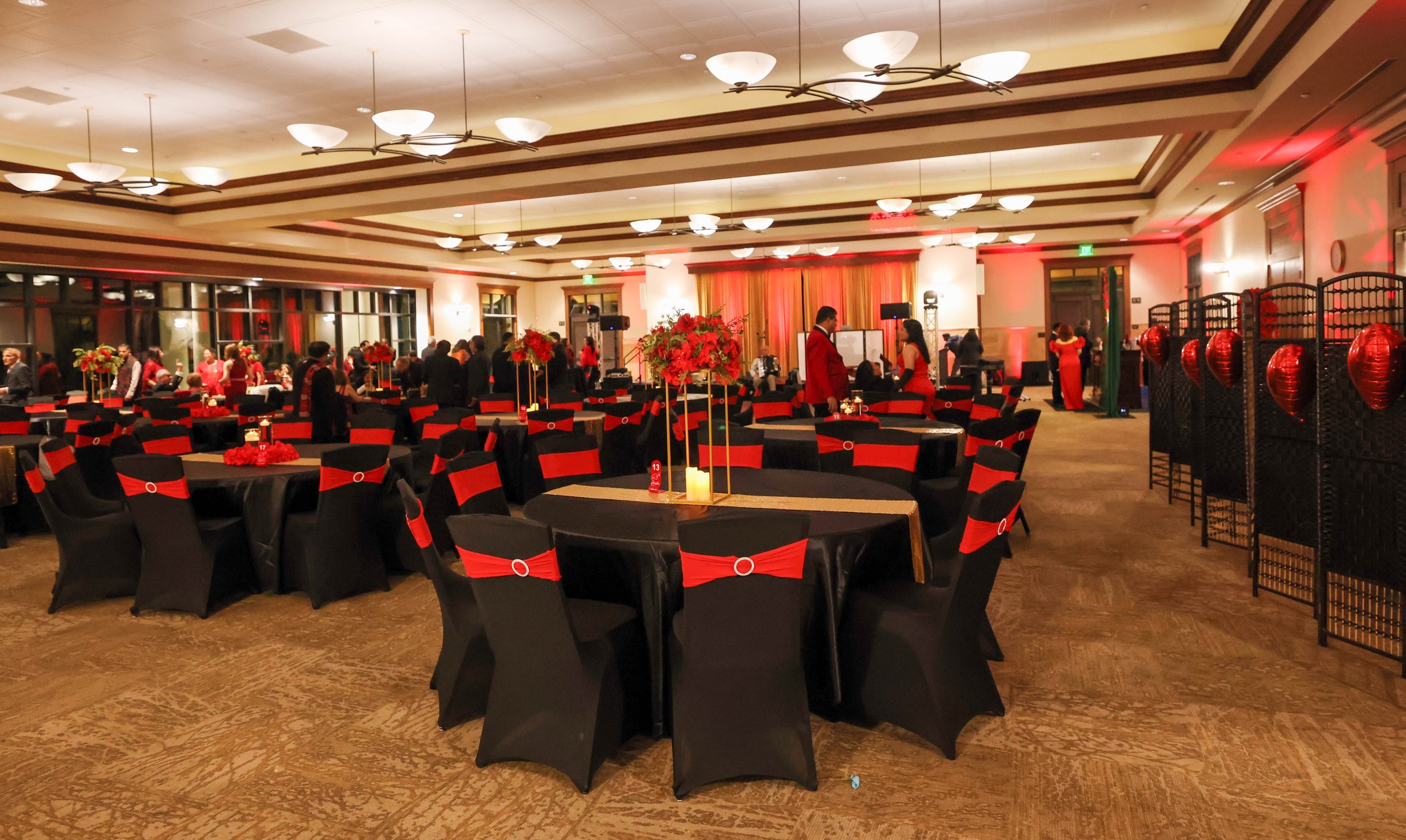 Grand gala ballroom reception styling with black linens, red chair accents, and elevated centerpieces